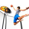 A boy in grey tanktop and blue shorts playss with a trampoline basketball hoop set