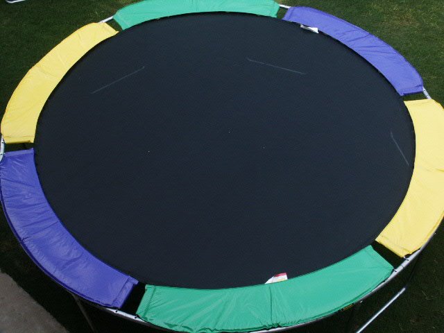 An overhead view of a purple, yellow, and green trampoline without net enclosure