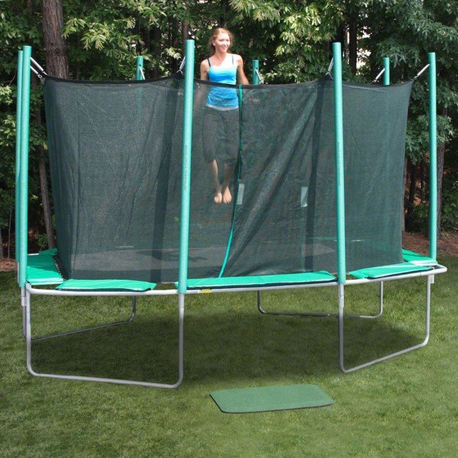 A cute teenage girl dressed in blue tank top and yoga pants jumps on a Magic Circle trampoline