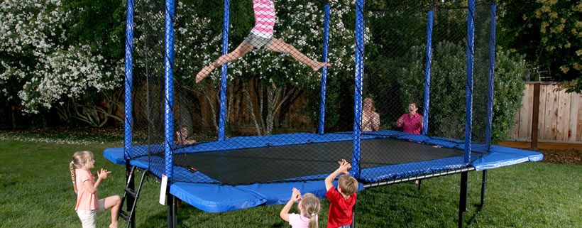 A little girl does gymnastics tricks on her rectangular trampoline