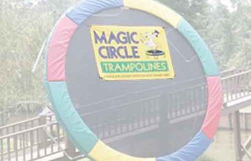 A Magic Circle trampoline leaned up against a fence