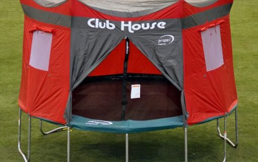 A red, trampoline clubhouse on a propel trampolines in the middle of a park