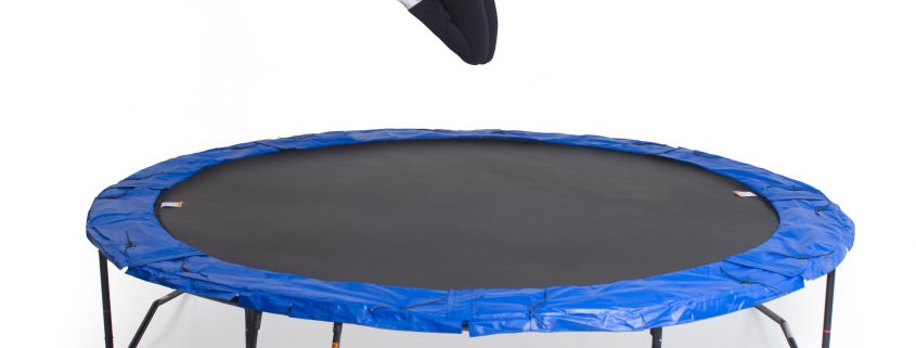A woman bouncing and posing on a JumpSport trampoline without safety enclosure