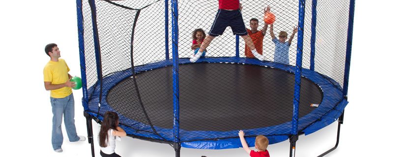 a kid flexing his muscles, while a group of kids watch him jump on a JumpSport trampoline