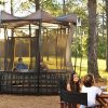 A mother and two kids sit at a camping table in the woods next to their Vuly Thunder tent