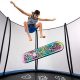 A boy jumps above a colorful trampoline skate deck