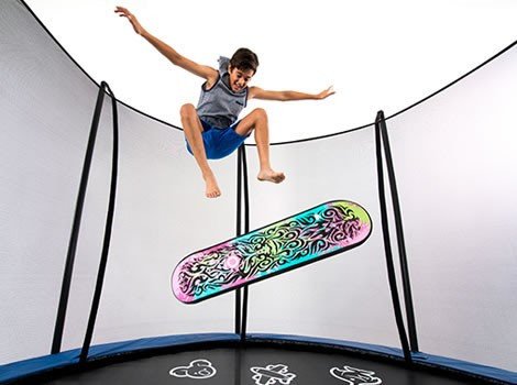 A boy jumps above a colorful trampoline skate deck