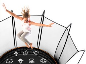Girl in grey pants and white shirt flails her arms as she jumps on a tramp