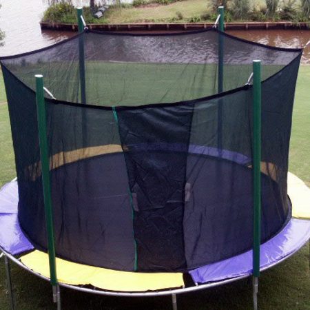 A round trampoline with net on a golf course next to a river