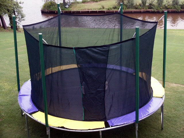 A round trampoline with net on a golf course next to a river