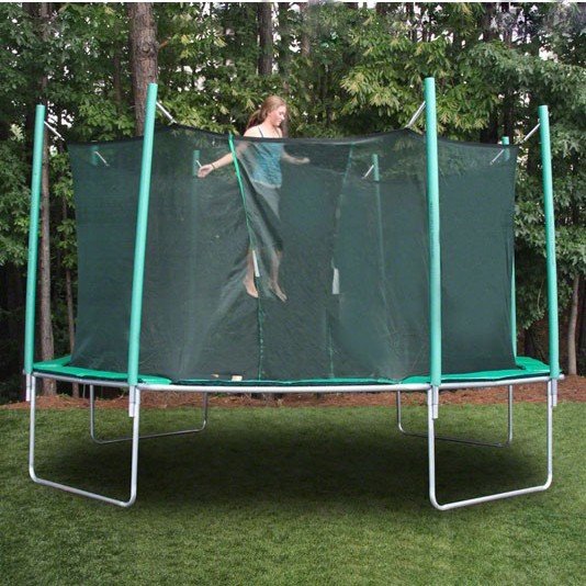 A teenage girl jumps on a green trampoline with net.