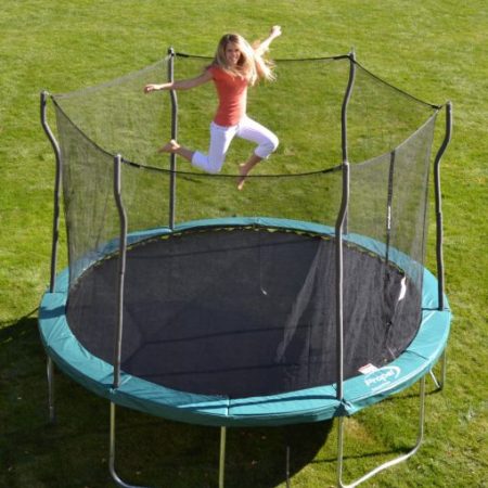 Blond mom jumping on turqouise trampoline in backyard