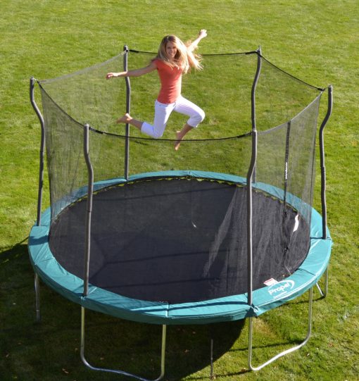 Blond mom jumping on turqouise trampoline in backyard