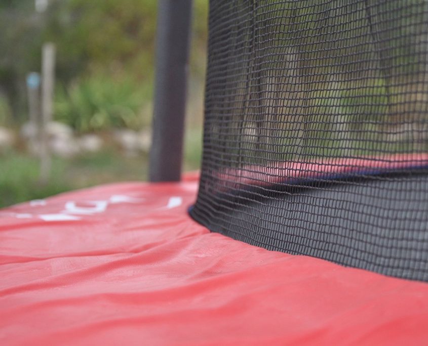 Close up picture of a red trampoline pad and safety net