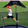 A 10-year old boy jumps to slam dunk his trampoline basketball hoop in his backyard