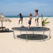 Two small children jump on trampoline at the beach