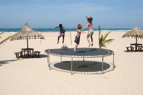 Two small children jump on trampoline at the beach