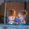 A brother and sister read while camping in their Vuly 2 Ttrampoline Tent