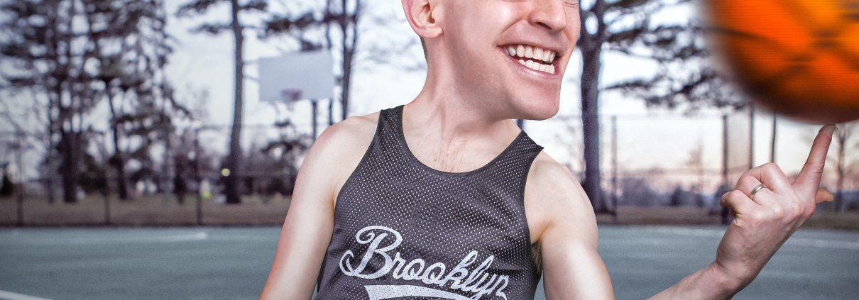 a crazy eyed man with a brooklyn shirt spins a basketball on his finger 