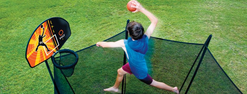 a young boy in blue shirt dunking his Vuly basketball hoop high above his Vuly 2 trampoline